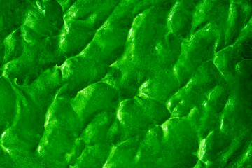 Smears of liquid green gel texture background. Smeared oil paint with pearly shine. Cream scrub to cleanse the skin of the face and body. Spa treatments, skin care.