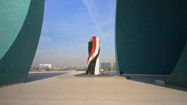 Person sitting in Martyrs Memorial Monument with sculpture of Iraqi flag colors in middle, Baghdad in Iraq.First person forward