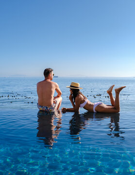 A Mature Couple Man And Woman In Front Of Infinity Pool Looking Out Over The Ocean Of Cape Town South Africa, Man And Woman In A Swimming Pool During Sunset. 