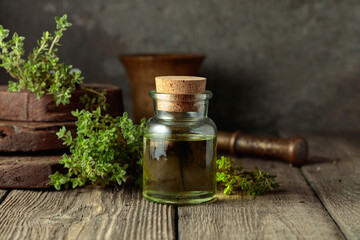 Obraz na płótnie Canvas Bottle of thyme essential oil with fresh thyme twigs.