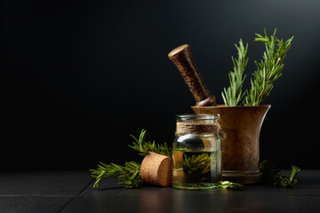Bottle of rosemary aromatherapy oil extract with fresh rosemary branches.