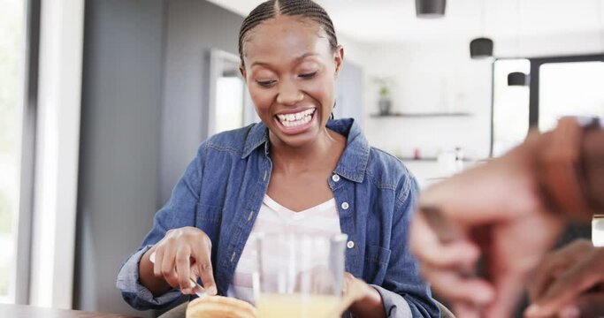 Happy african american couple having breakfast and talking at table in kitchen, slow motion