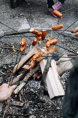 Thick sausages on metal skewers over a fire.