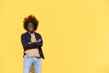 Cheerful and confident young man with arms crossed wearing sunglasess