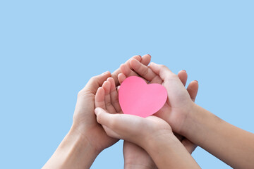 Heart in baby and mother hands isolated on blue background..Young woman and child holding heart in hands top view. Happy family relationships, love to mom, mother day, protect concept.Space for text..