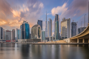 Long exposure at sunset in Dubai. Business center of the city with office buildings and skyscrapers around Burj Khalifa. Financial district skyline in the evening with cloudy skies.