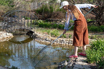 woman is cleaning garden pond from green algae