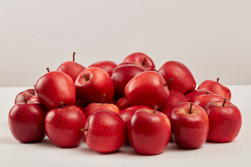 Ripe red apples are prominently displayed on a white background. Scene for advertising cosmetic or product with red apple ingredients, from natural origin and many uses for health and beauty
