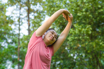 Young Asian woman in sportswear stretches before exercising in the park for a healthy lifestyle. Young healthy woman warming up outdoors. Healthy lifestyle concept.