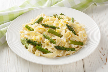 Asparagus Pasta with Lemon zest and Parmesan closeup on the plate on the wooden table. Horizontal