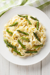 Lemony Asparagus Pasta fettuccine with parmesan cream sauce closeup on the plate on the wooden table. Vertical top view from above