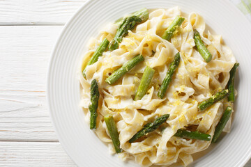 Creamy Lemony Asparagus Pasta fettuccine closeup on the plate on the wooden table. Horizontal top view from above
