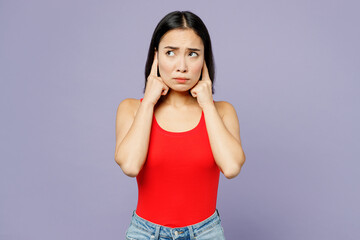Obraz na płótnie Canvas Young woman of Asian ethnicity she wearing casual clothes red tank shirt cover ears with hands fingers do not want to listen scream isolated on plain pastel light purple background. Lifestyle concept.