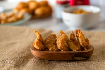 Crispy prawns served on a wooden plate in a traditional kitchen composition