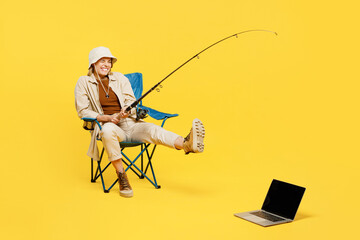 Full body young woman sit near laptop pc computer hold fishing rod pov pull isolated on plain...