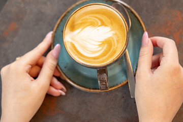 Female hands with a cappuccino cup in a cafe