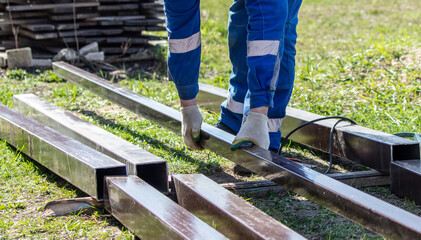 A worker in blue overalls works with metal pipes at a construction site