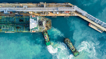 Aerial view oil tanker ship at terminal industrial port tugboat drag crude oil tanker ship park to...