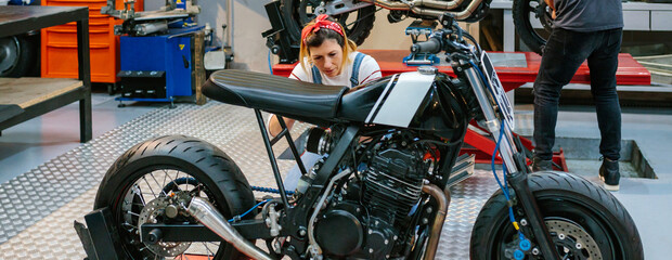 Female mechanic checking custom motorcycle on garage