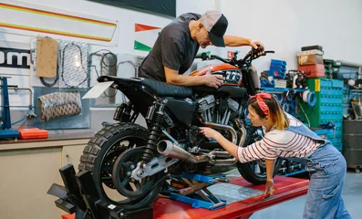Photo sur Plexiglas Moto Mechanic couple team reviewing engine of custom motorbike over platform on factory