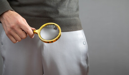 Man with a magnifying glass looking his penis.