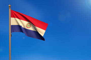 Paraguay. Flag blown by the wind with blue sky in the background.