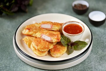 Crab sticks in batter in a frying pan.