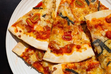 Pizza in white plate on dark background.