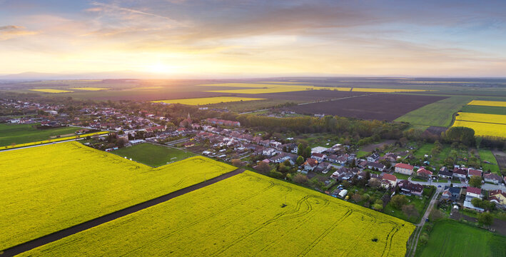 Drone view of rural field landscape with village at dramatic sunset