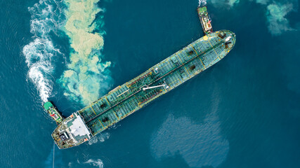 Aerial view oil tanker ship at terminal industrial port tugboat drag crude oil tanker ship park to...