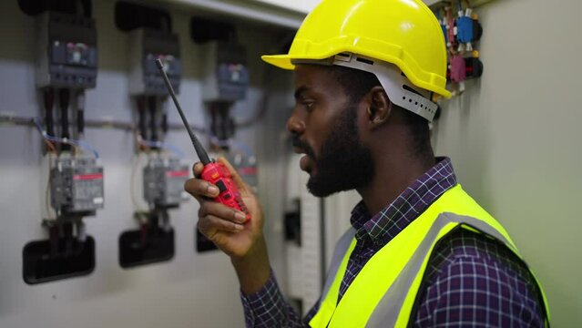 Industry factory manufacturing concept. African man engineer working in electric server control panel room. Industrial technician worker speaking on walkie talkie with colleague in power system room.