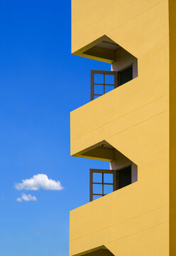 Exterior architecture background in minimal style of open glass doors of fire escape on modern yellow apartment building against blue sky in vertical frame