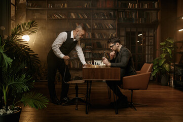 Two nervous chess players looking at chessboard over cozy home interior