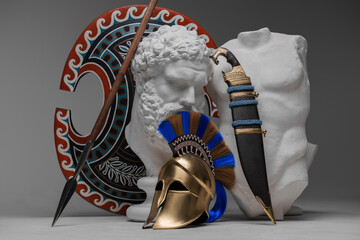 Shot of greek bust with body and weapons of soldier against gray background.