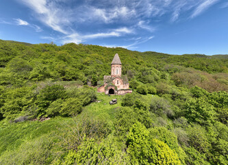Fototapeta na wymiar the ancient church hid in the forest in the gorge of the mountains of Armenia taken from a drone