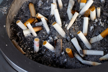 Cigarettes and ash on dirty sand in trash tray