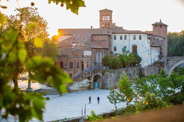 Isola Tiberina or Isola Tiberina in Rome.Italy. Isola dei Due Ponti, Licaonia, San Bartolomeo Island at sunset. An ancient river island of the Tiber with historical monuments, center of Rome. - obrazy, fototapety, plakaty