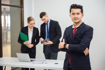 Asian smart male businessman Confident smiling business boss standing in office at team meeting Portrait of confident business man with colleague in conference room