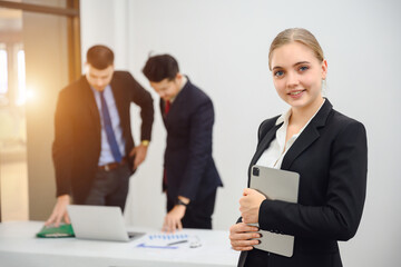 Fototapeta premium Portrait of young businesswoman looking at camera Confident smiling business boss standing in office at team meeting Portrait of confident businesswoman with colleague in conference room