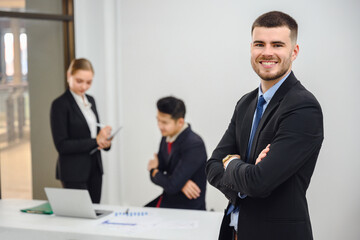 Portrait of a happy smiling businessman looking at the camera in a conference room Handsome working manager smiling confidently standing in office at team meeting