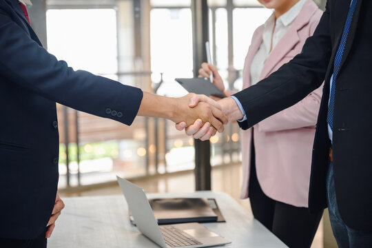 Close up of businessman or manager handshake with young businesswoman business partners shaking hands in the office Concept of three businessman partnership