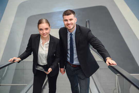 Portrait of a business man and two business women smiling happily and confidently while walking on an escalator. business discussion work together to work at the office