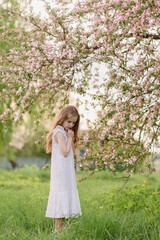 Fototapeta na wymiar a girl in a green summer park looking at a flower
