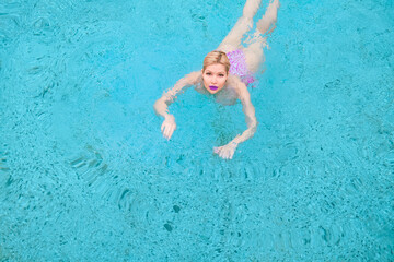 Fototapeta na wymiar A beautiful woman swimming in the pool. View from above. A shot from the air. View from above.