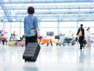 Fototapeta na wymiar 空港でスーツケースを持って旅行に出発する女性のイメージ