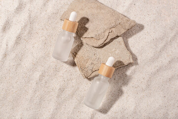 Glass bottles with a cosmetic product on a natural sandy background. Top view.