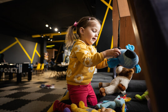 Baby girl playing with soft toys at modern kindergarten.