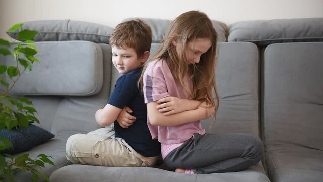 offended brothers and sisters sit back to back on the couch. children's emotions