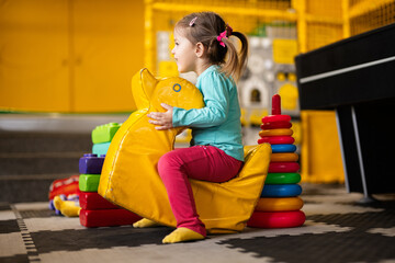 Baby girl swings on yellow paralon duck at kindergarten.