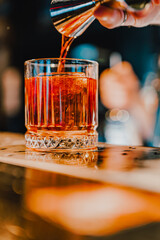man bartender hand making negroni cocktail. Negroni classic cocktail and gin short drink with sweet vermouth, red bitter liqueur